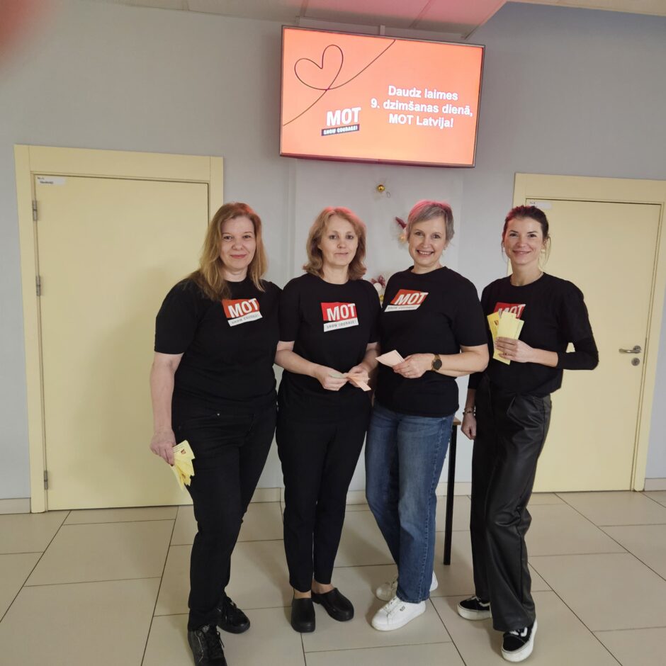 MOT treneres Ilze Briede, Santa Glazīrina, Gita Brodzinska un Katrīna Savicka pie televizora skolas 1.stāva gaitenī