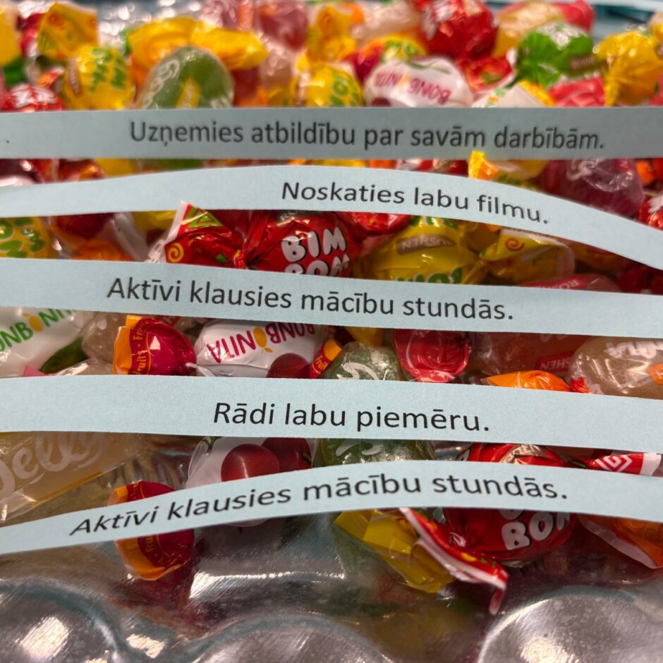 Attēlā redzamas konfektes, kurām pa virsu ir lapiņas ar iedvesmojošiem citātiem