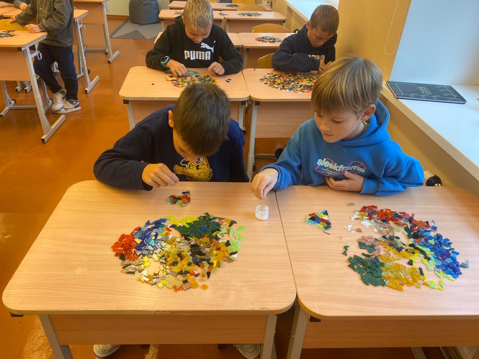 4 zēni liek stikla gabaliņus.