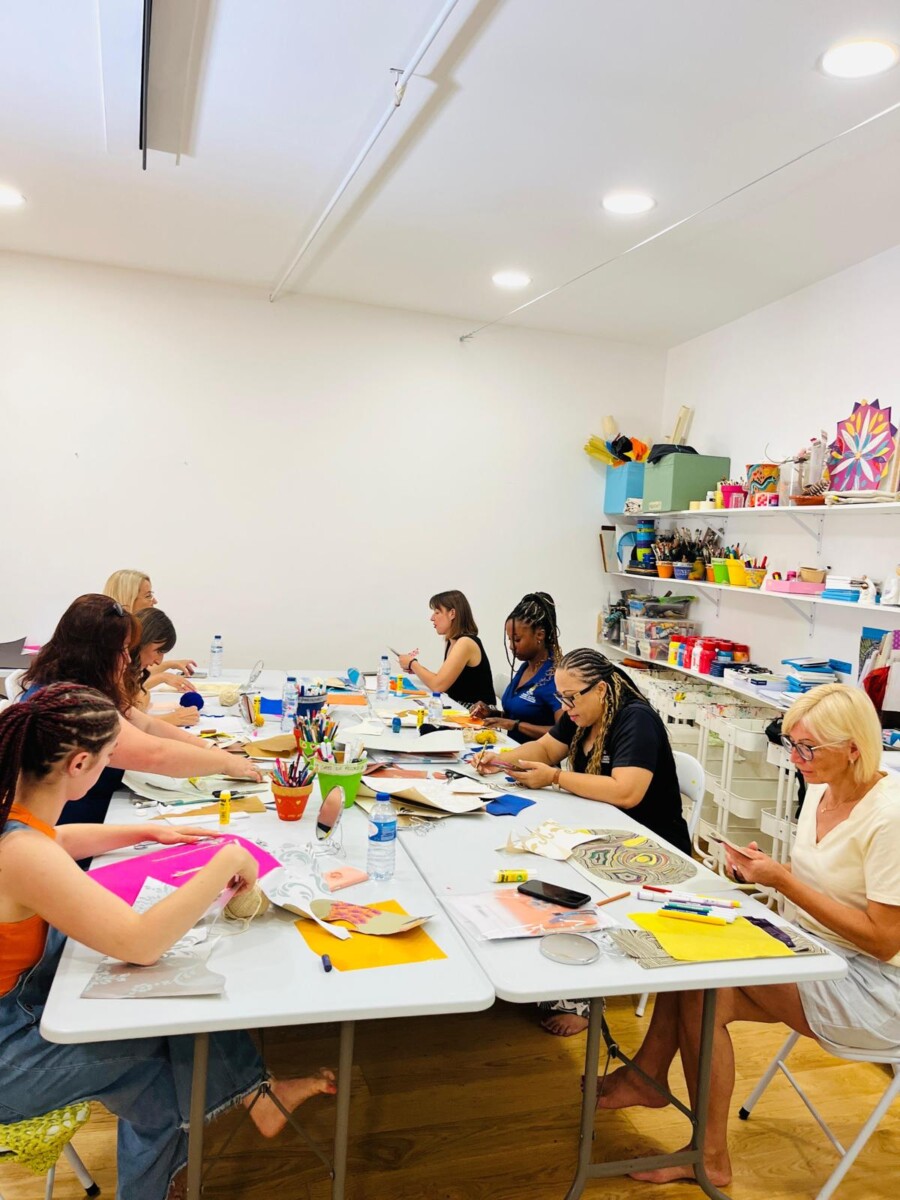 Kursu dalībnieki pie galda strādā ar krāsainu papīru