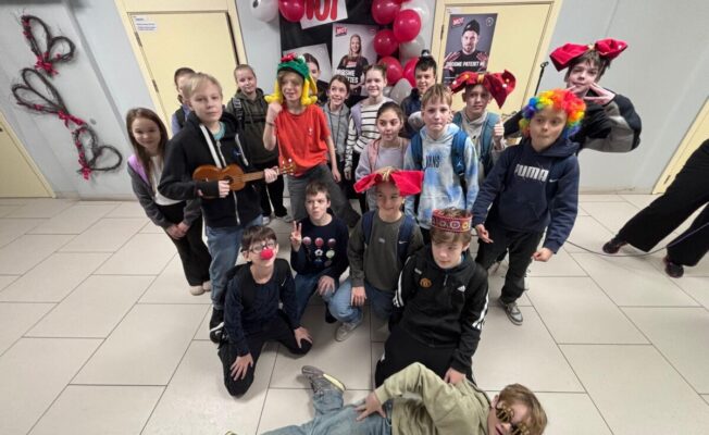 Skolēni ar dažādiem aksesuāriem, kuri pozē foto stūrītī