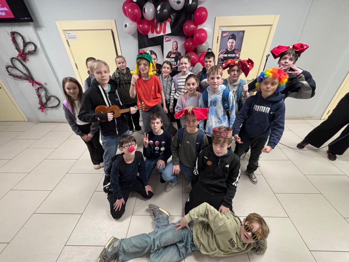 Skolēni ar dažādiem aksesuāriem, kuri pozē foto stūrītī