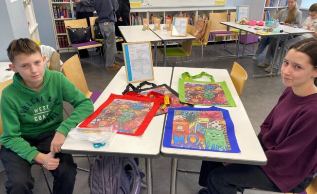 Divi skolni uz soliem demonstrē savus darbus