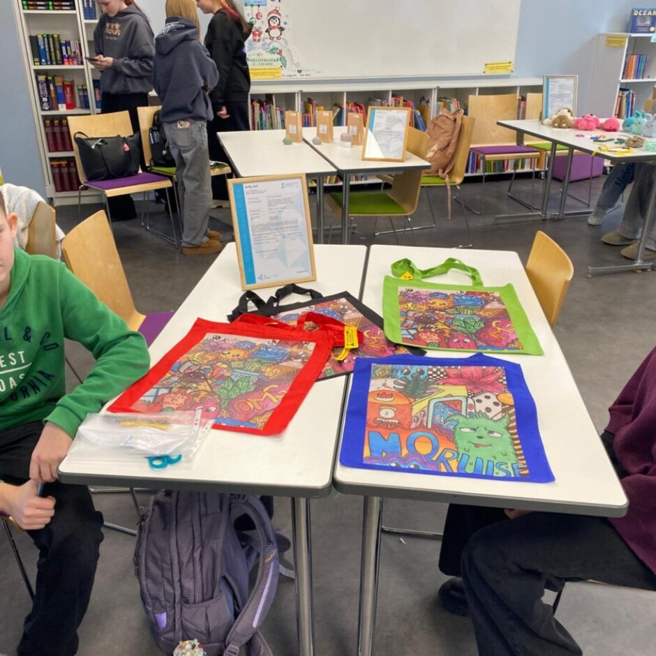 Divi skolni uz soliem demonstrē savus darbus