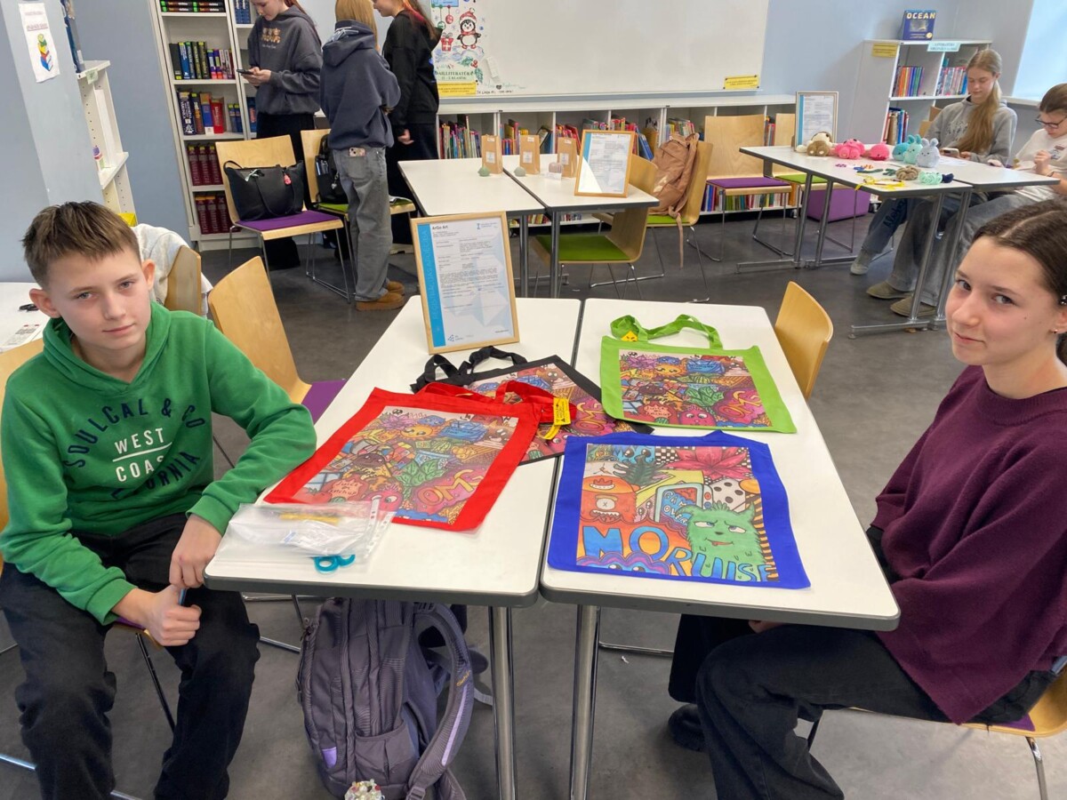 Divi skolni uz soliem demonstrē savus darbus