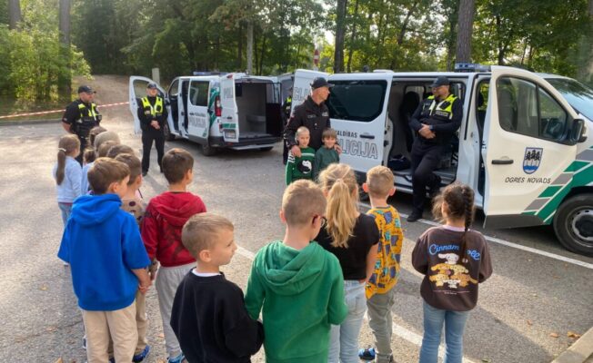 Pirmklasnieku grupa pie policijas mašīnām