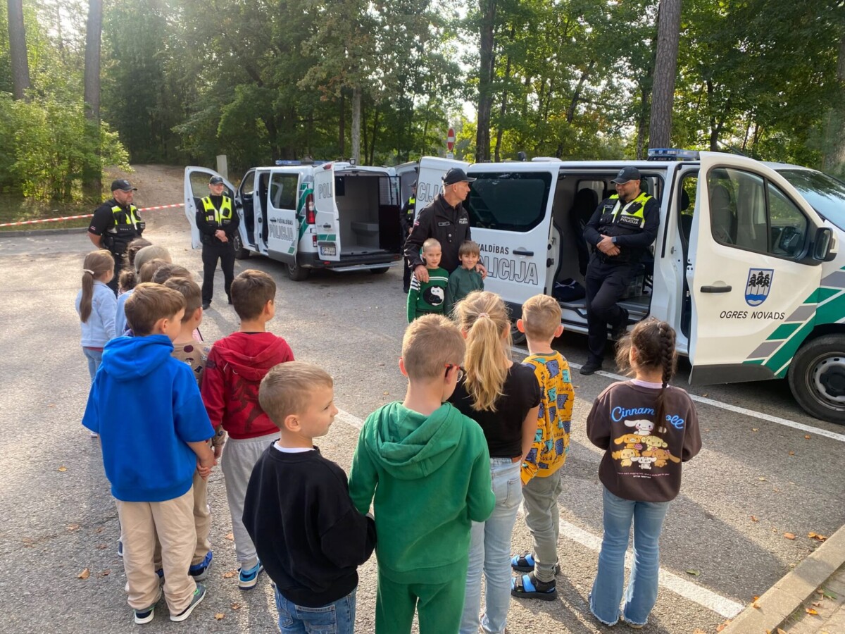Pirmklasnieku grupa pie policijas mašīnām